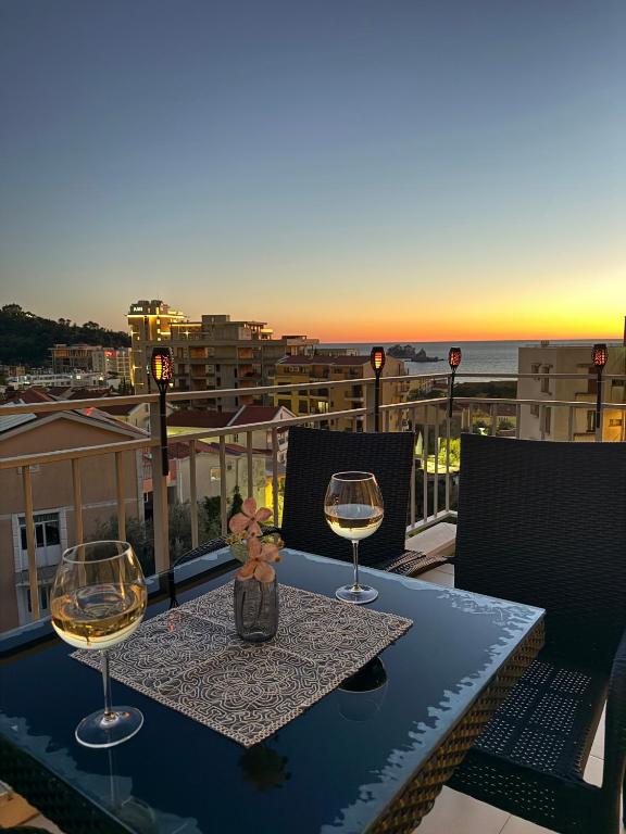 a table with two wine glasses on a balcony at Petrovac Pearl Apartment in Petrovac na Moru