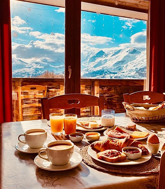 a table with plates of food and cups of coffee at T2 cosy 4 pers balcon vue montagne la Joue du loup in Le Dévoluy