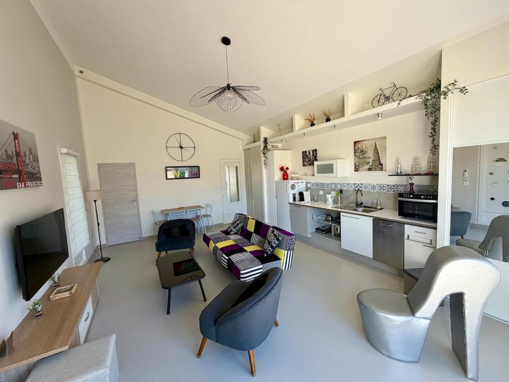 a living room with a couch and chairs and a kitchen at Maison au calme proche accès rocade in Montauban