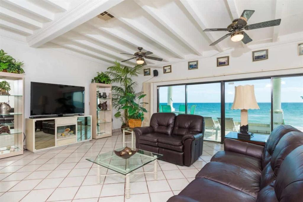 a living room with a couch and a television and the ocean at Comfortable Beachfront Condo Las Olas II 1 in Puerto Peñasco