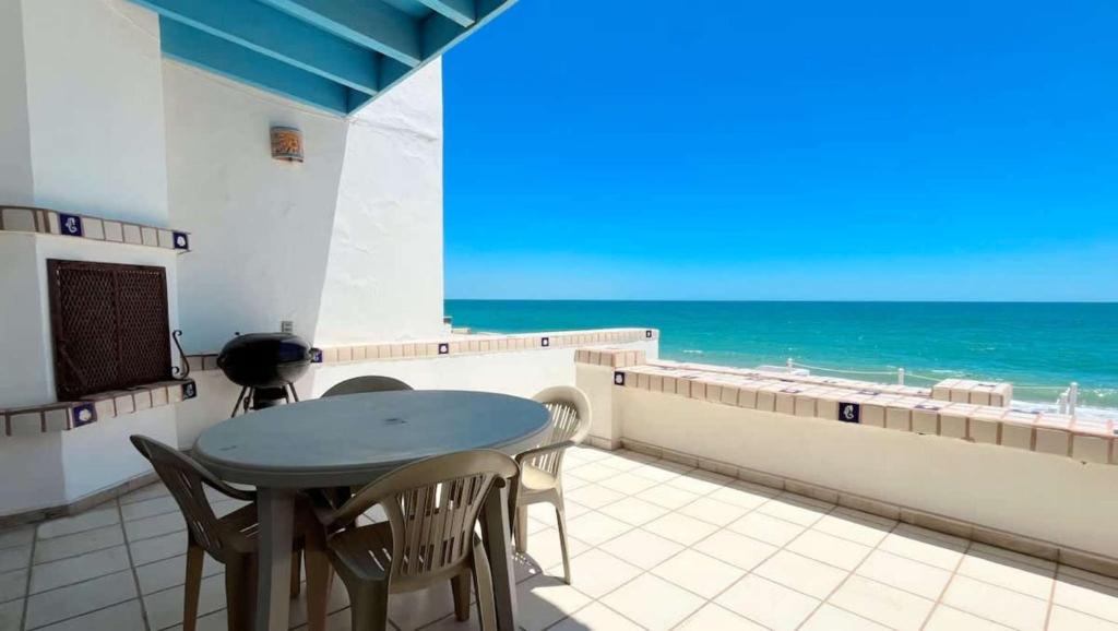 a table and chairs on a balcony with the ocean at Cozy & Colorful Beachfront Condo Las Olas II 4 in Puerto Peñasco