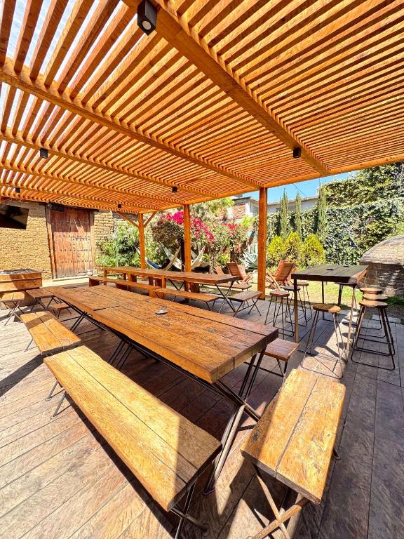 a wooden pergola with benches and tables on a deck at Puerta Vieja Hostel in San Cristóbal de Las Casas