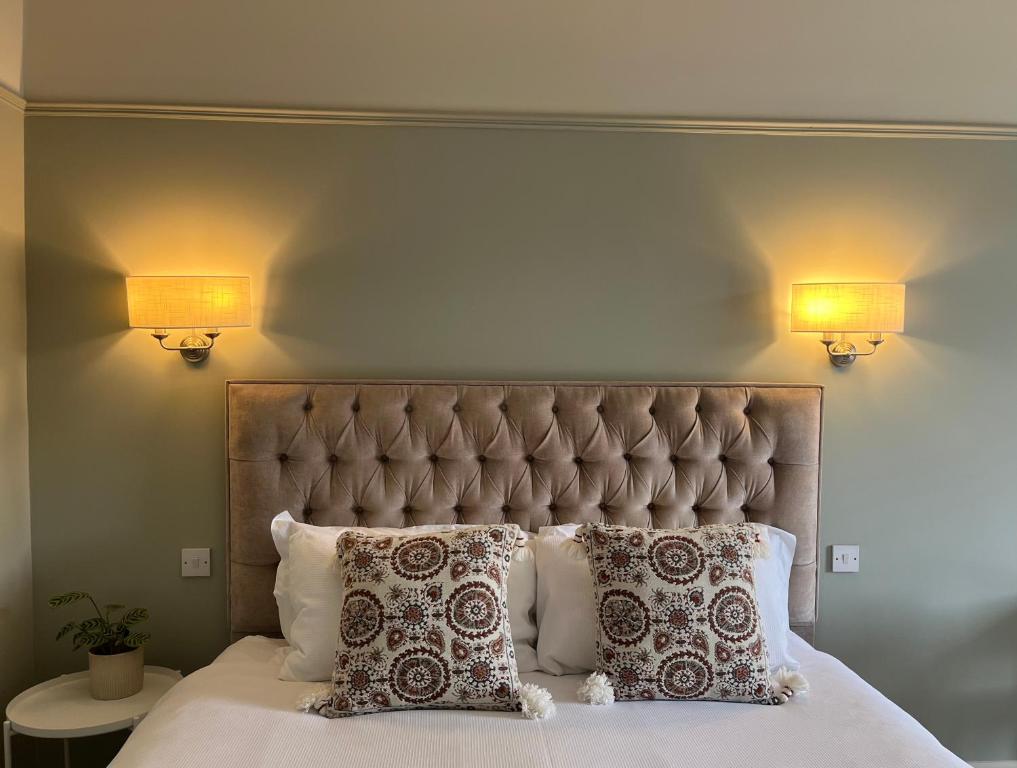 a bed with two lamps on the wall and two pillows at The Doonleigh suite in Ayr