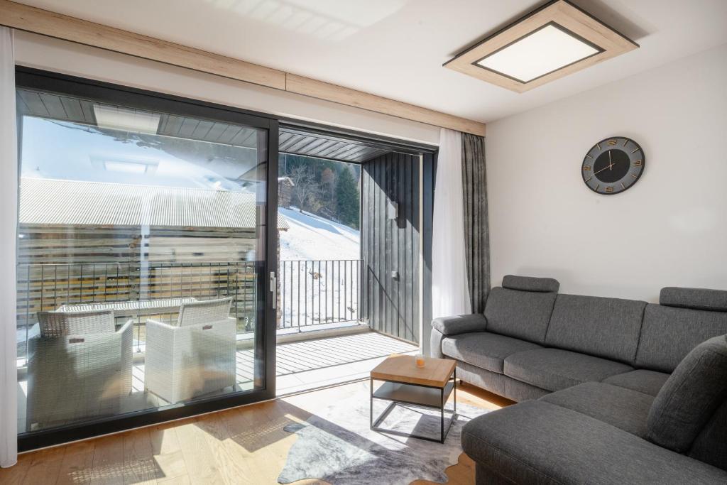 a living room with a couch and a sliding glass door at Moderne Wohnung mit einer wunderschönen Aussicht in der Residenz Silvretta, inkl Silvretta Card Premium in See