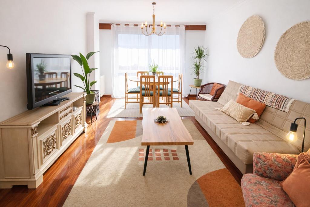 a living room with a couch and a tv at Holibai Amieiro Apto amplio y luminoso cerca de la playa, Baiona in Baiona