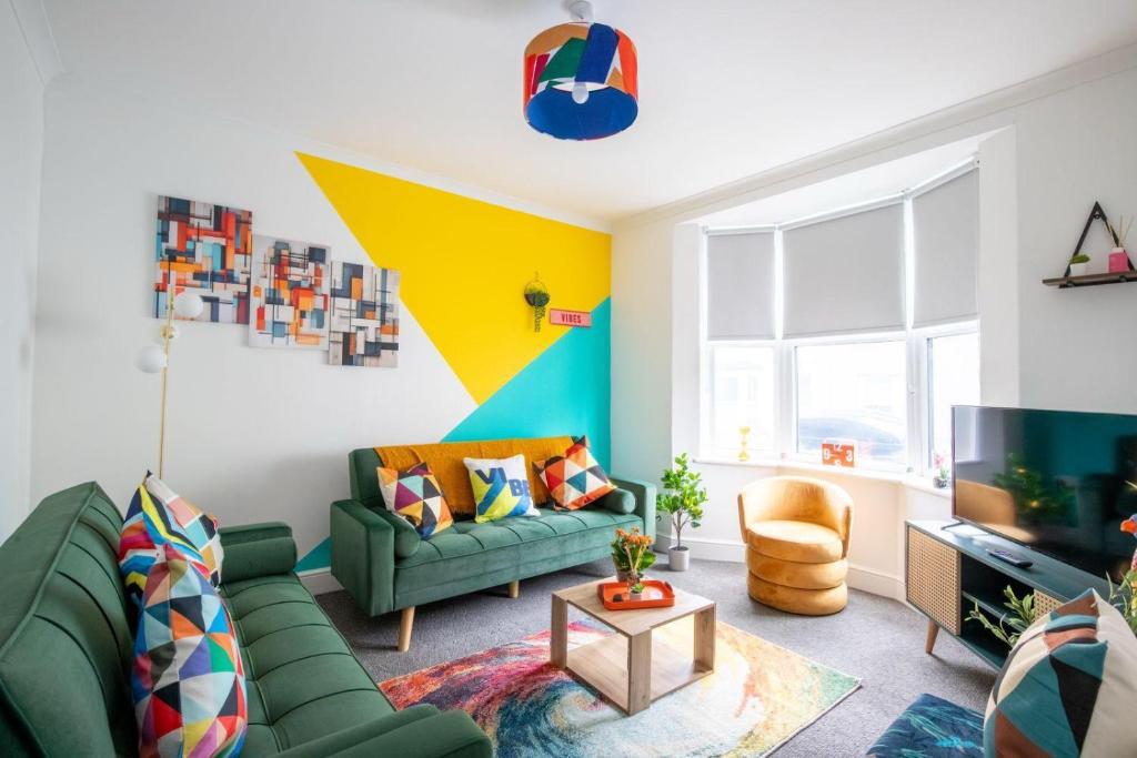 a living room with a green couch and a tv at Brighton Colour Pop House- Sleeps up to 12 in Brighton & Hove