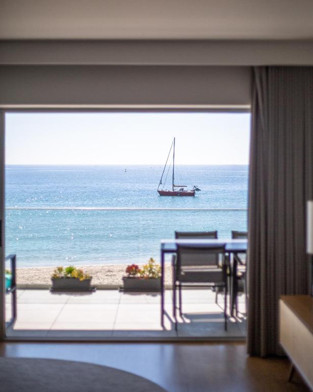 a room with a view of the ocean and a sail boat at Sesimbra Ocean Terrace in Sesimbra
