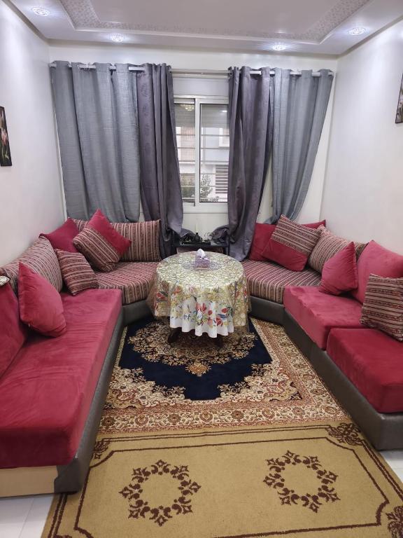 a living room with red couches and a table at Duplex al menzah in Tamaris