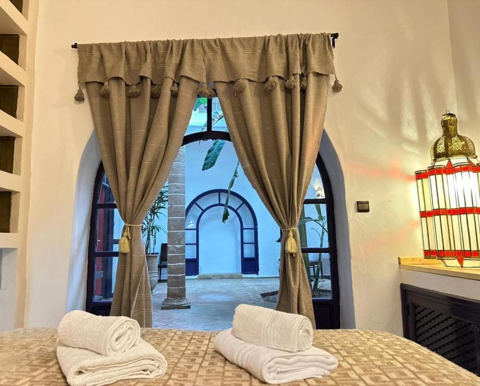 a bedroom with a bed and a large window at Riad Medina Charme et Sérénité in Essaouira