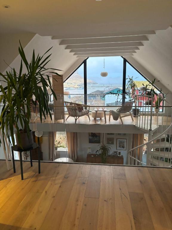 a living room with a table and a large window at Design Villa with Panoramic Views & Large Windows in Miðvágur