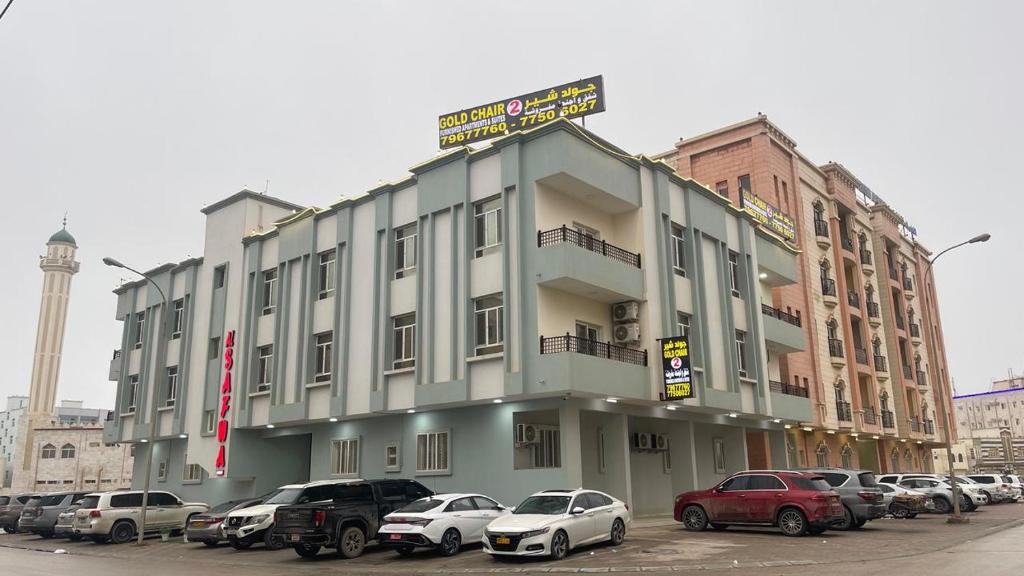 a large building with cars parked in a parking lot at قولد شير 2 in Salalah