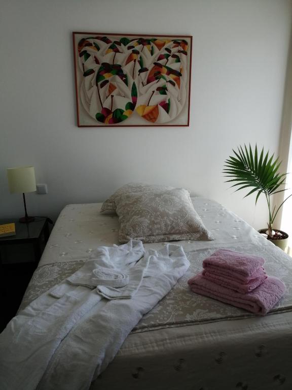 a bed with clothes on it with a painting on the wall at Sunny Ofir in Fão
