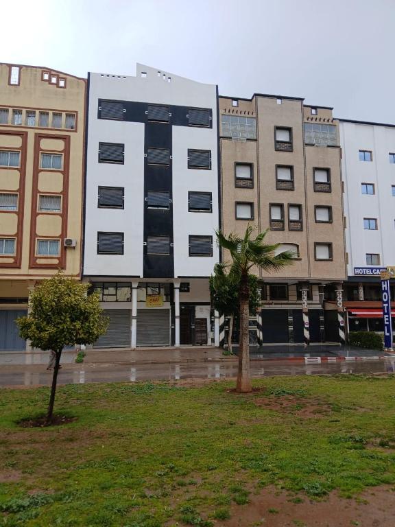 a building in the rain with a palm tree in front at تجزئة الفتح 925 خريبكة 3 in Khouribga