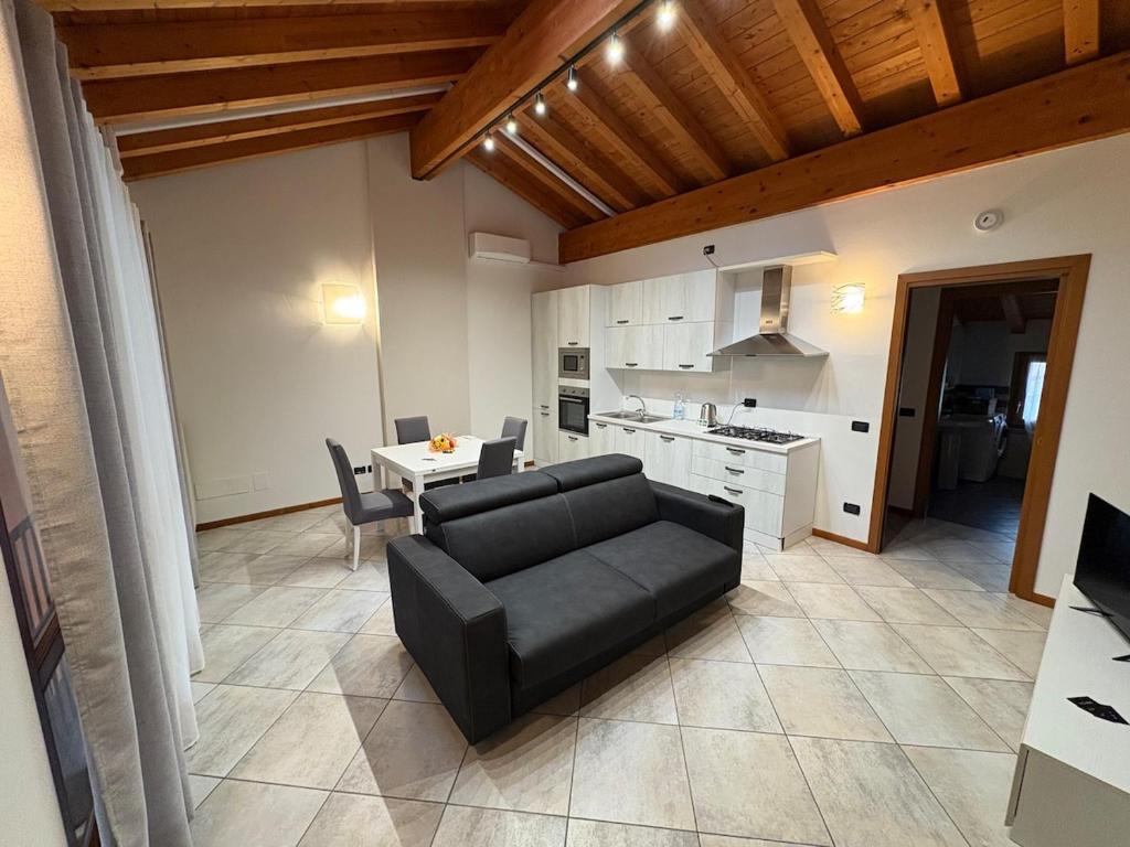 a living room with a black couch and a kitchen at Hub 2A in Calcio