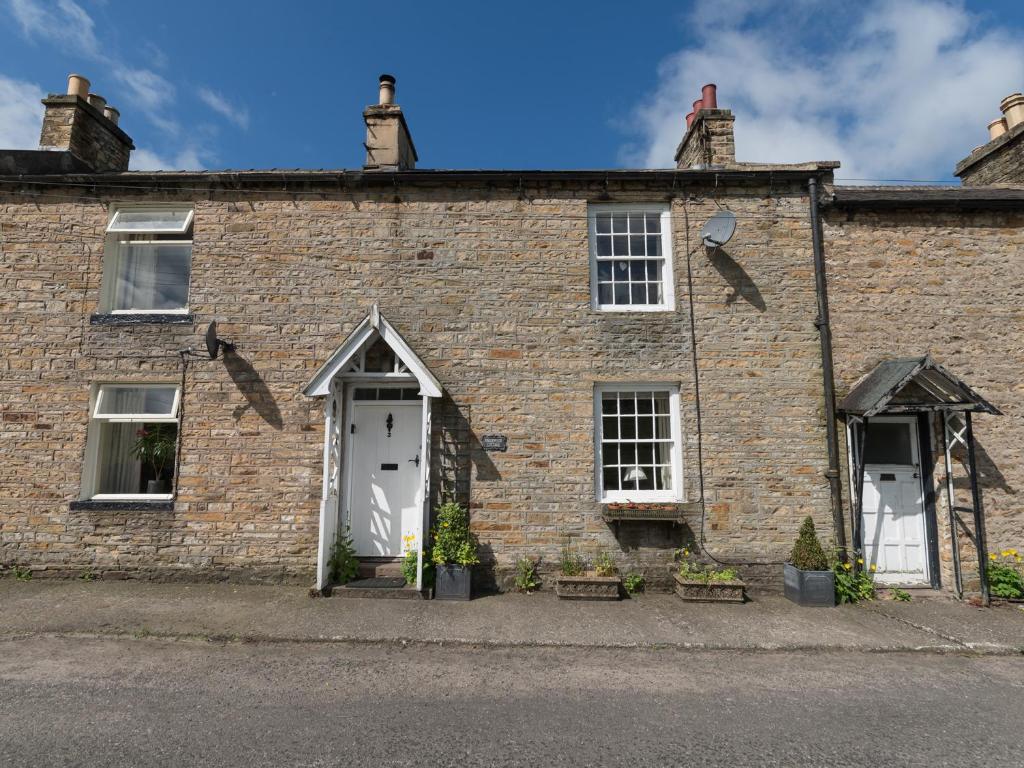 an old brick building with white doors and windows at Englewood Cottage in Hexham