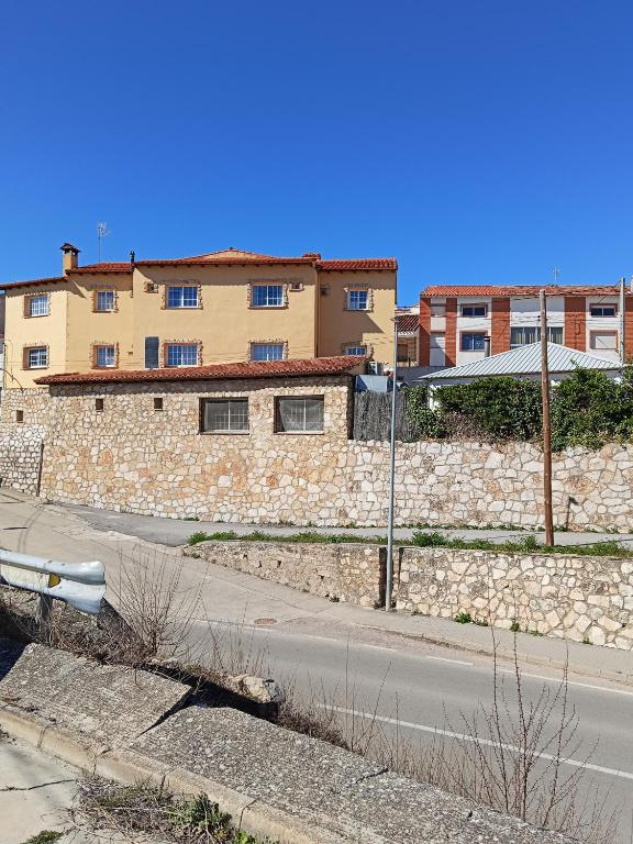 a stone wall next to a street with a building at La murallita de Aroa in Cañete