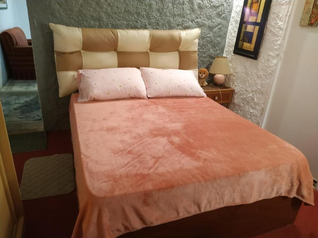 a bedroom with a bed with an orange blanket at Alojamiento Victoria in Montevideo