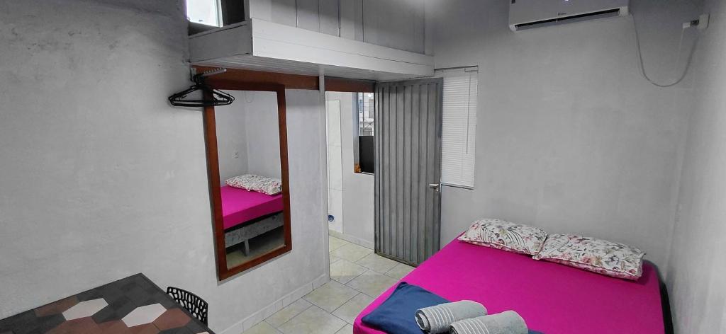 a small room with a pink bed and a mirror at Pousada Familiar 03 in Rio do Sul