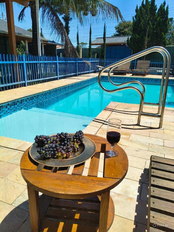 a plate of food and a glass of wine next to a pool at Recanto Vila Madalena in Caçapava