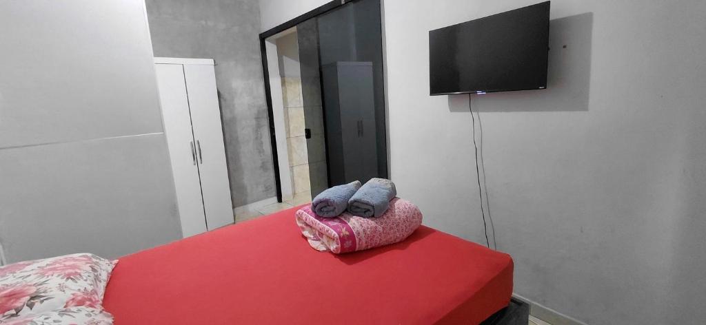 a room with a red table and a tv on a wall at Pousada familiar 02 in Rio do Sul