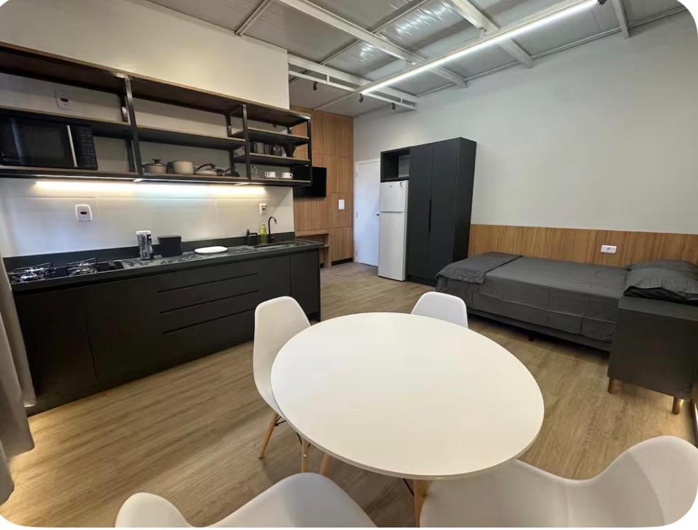 a room with a table and chairs and a bed at Studios Botânico in Curitiba