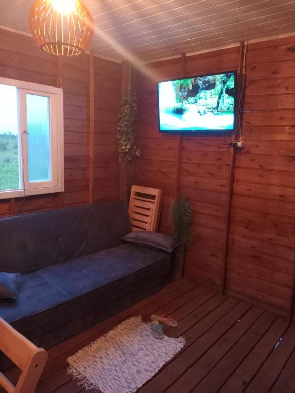 a living room with a couch and a flat screen tv at Recanto do sol in Imaruí