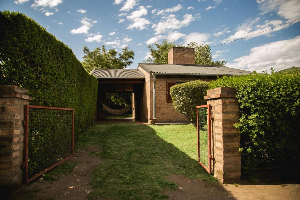 een ingang naar een huis met een hek en heggen bij La Pausa in Santa Rosa de Calamuchita