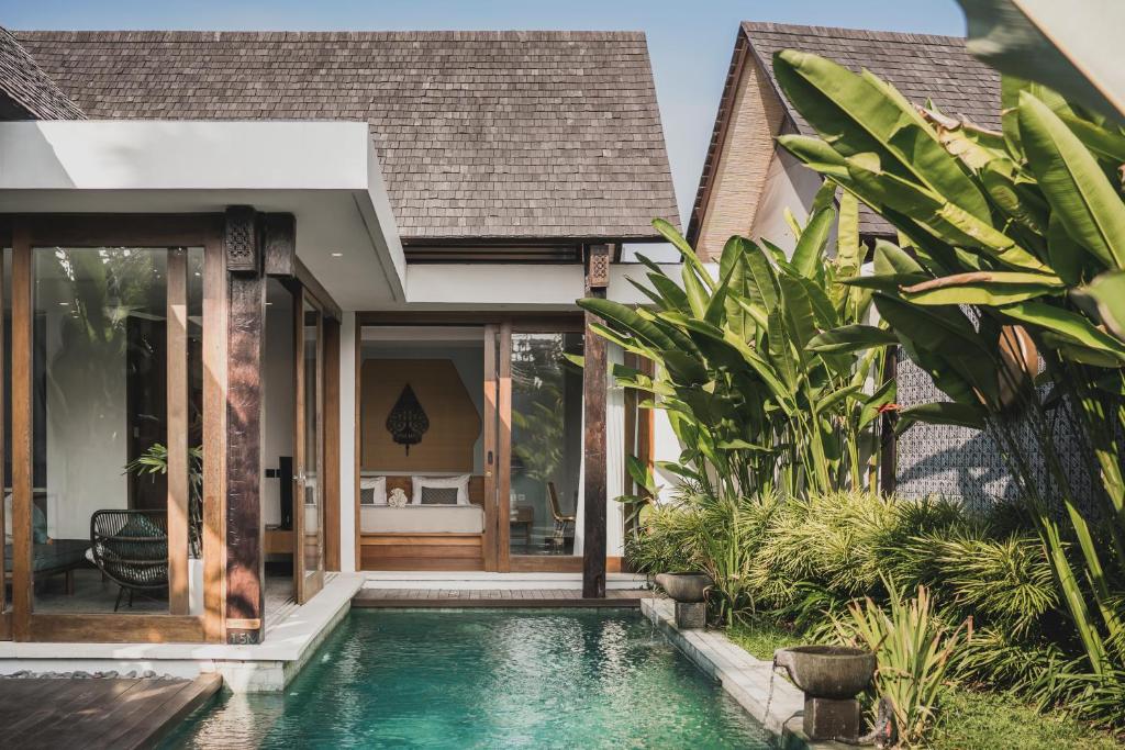a villa with a swimming pool in front of a house at Sanora Villa Sanur by Ini Vie Hospitality in Sanur