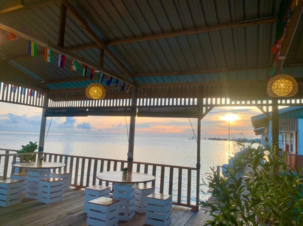 a patio with tables and chairs and the ocean at BIHING ANGAN water chalets in Semporna