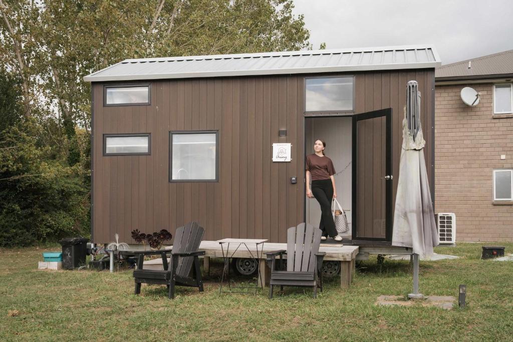 a woman standing in the doorway of a tiny house at Sweet Hart 1 by Tiny Away in Tamahere