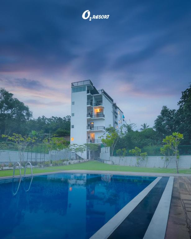a hotel with a swimming pool in front of a building at O2 Resort Welimada in Nugatalawa
