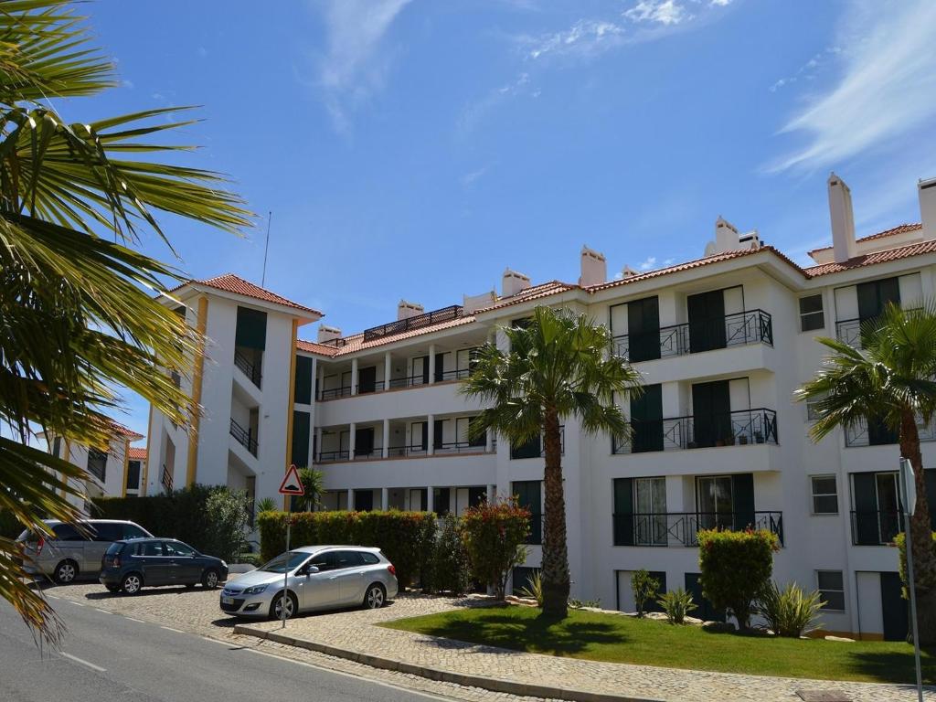 a large white building with cars parked in a parking lot at Sunny Balcony Apartment and Pool in Vilamoura