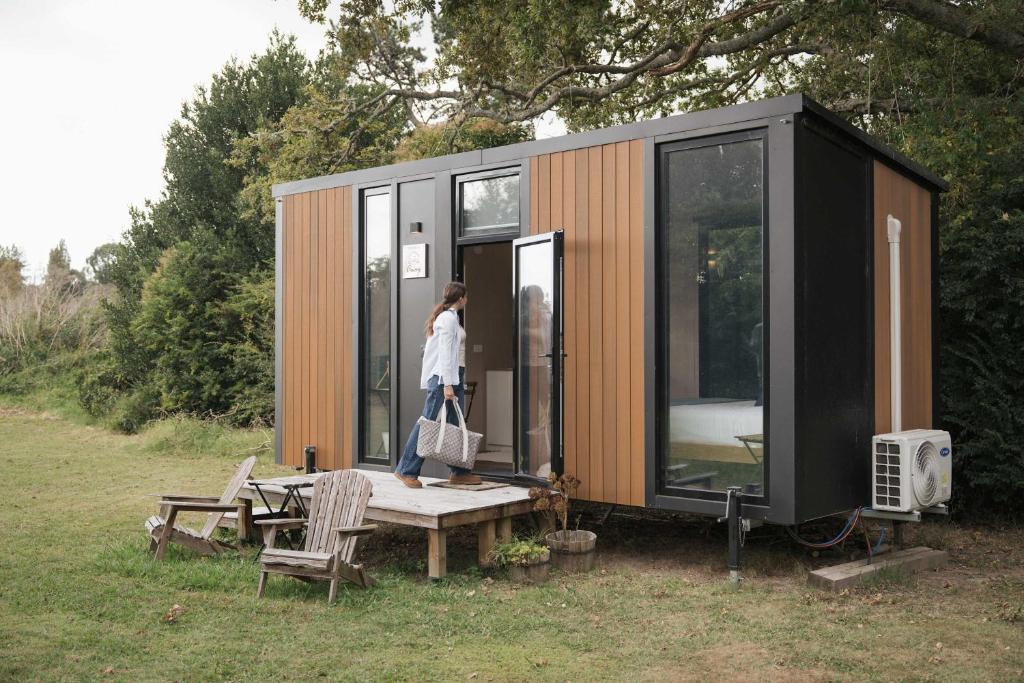 a woman is standing outside of a tiny house at Sweet Hart 2 by Tiny Away in Tamahere