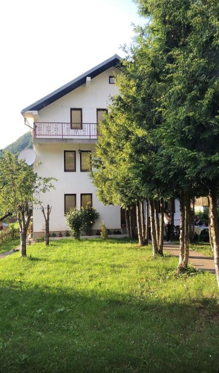 a large white building with trees in front of it at Highland guest house Vuthaj in Vusanje