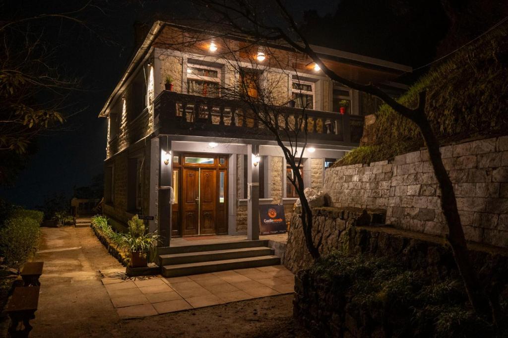 a house with lights on the front of it at night at Trippers CastleWoods in Darjeeling