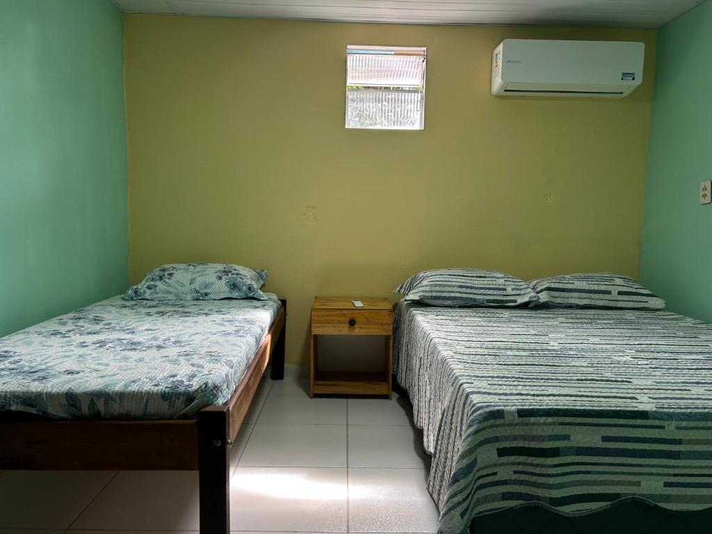 a bedroom with two beds and a night stand and a window at Quarto Sairé in Santarém