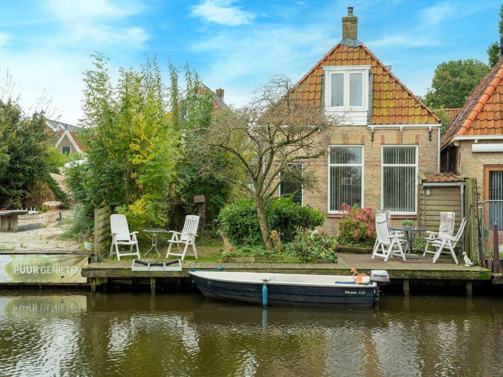 a boat on the water in front of a house at Waterside stay with Private Jetty in Heeg