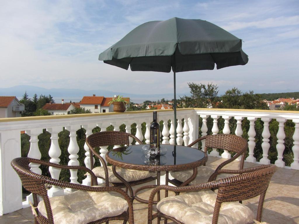 a table and chairs with an umbrella on a balcony at Apartments I-P in Malinska