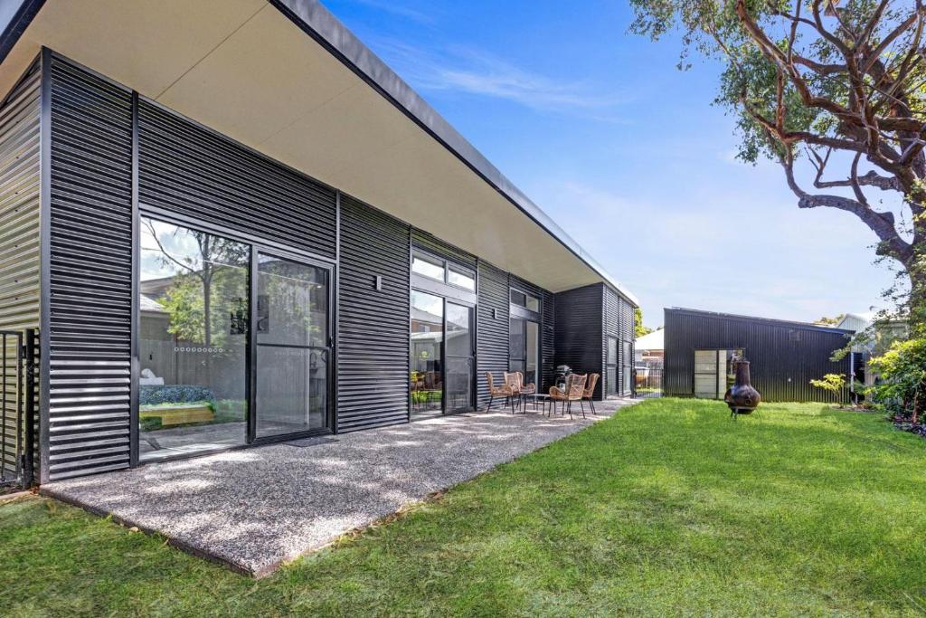 a modern house with black siding and a yard at Sheoak in Paynesville