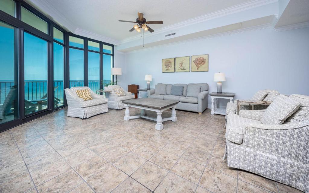 a living room with couches and a table and windows at Phoenix West 603 in Orange Beach