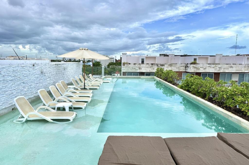 a swimming pool with lounge chairs and the water at Anah Suites by Las Flores Vacation Rentals in Playa del Carmen