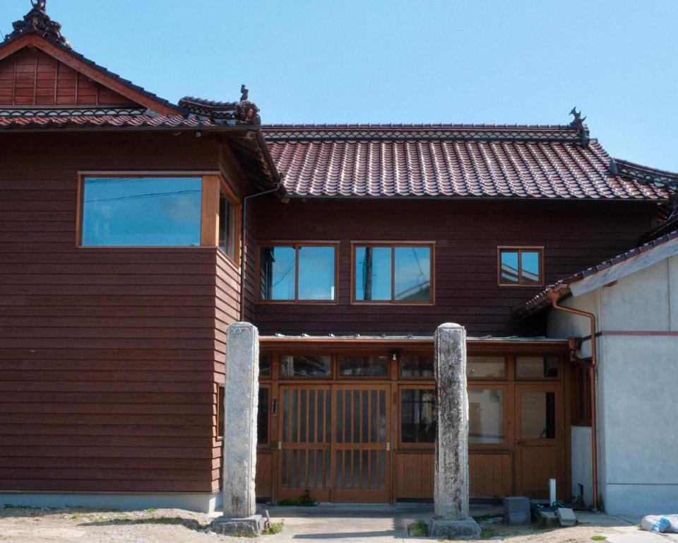 a wooden house with two stone pillars in front of it at Omoya Kitahata in Karatsu