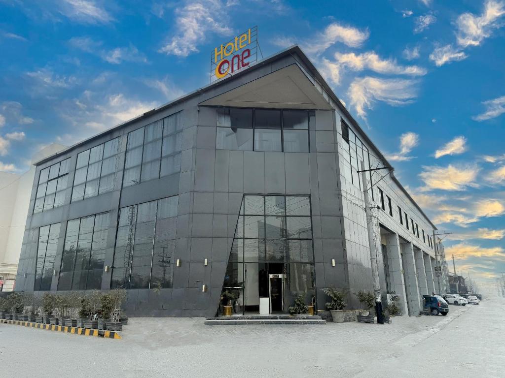 a large glass building with a sign on top of it at Hotel One Gujranwala in Kot Mergulla