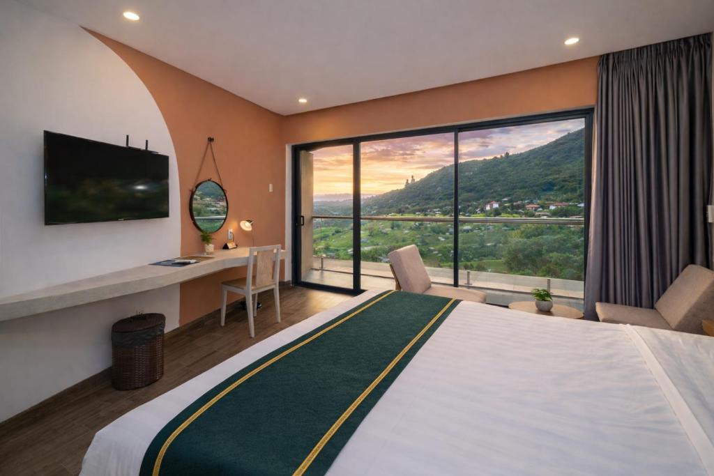a hotel room with a bed and a desk and a large window at La Cactus Oceanview Resort Quy Nhon in Quy Nhon