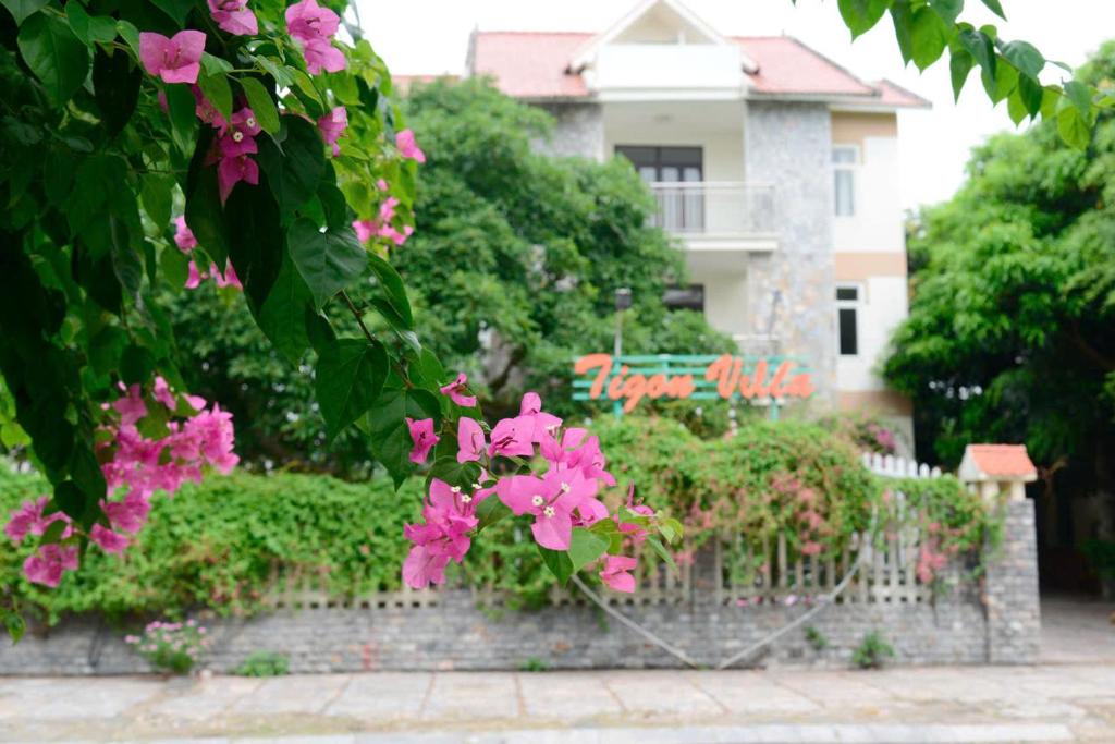 a fence with pink flowers in front of a house at Tigon Villa in Mỹ Ðuc