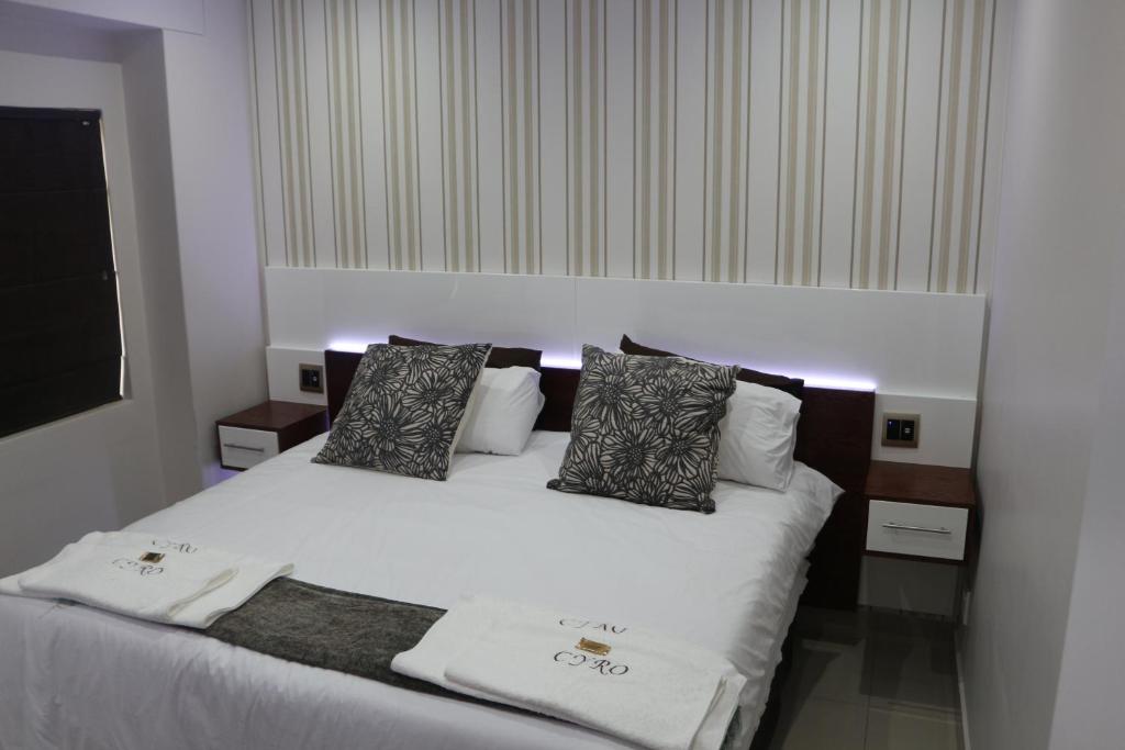 a bedroom with a bed with white sheets and pillows at Cyro Apartments at Central Park in Durban