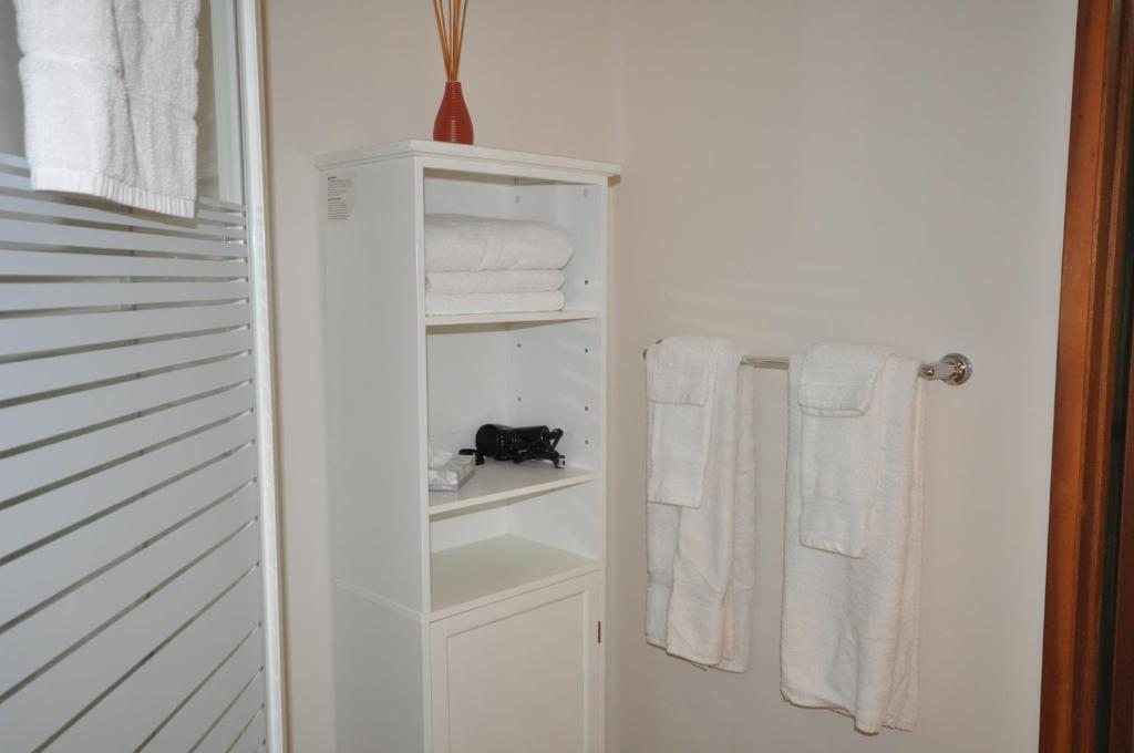a bathroom with white towels and a black cat on a shelf at Garden House in Courtenay