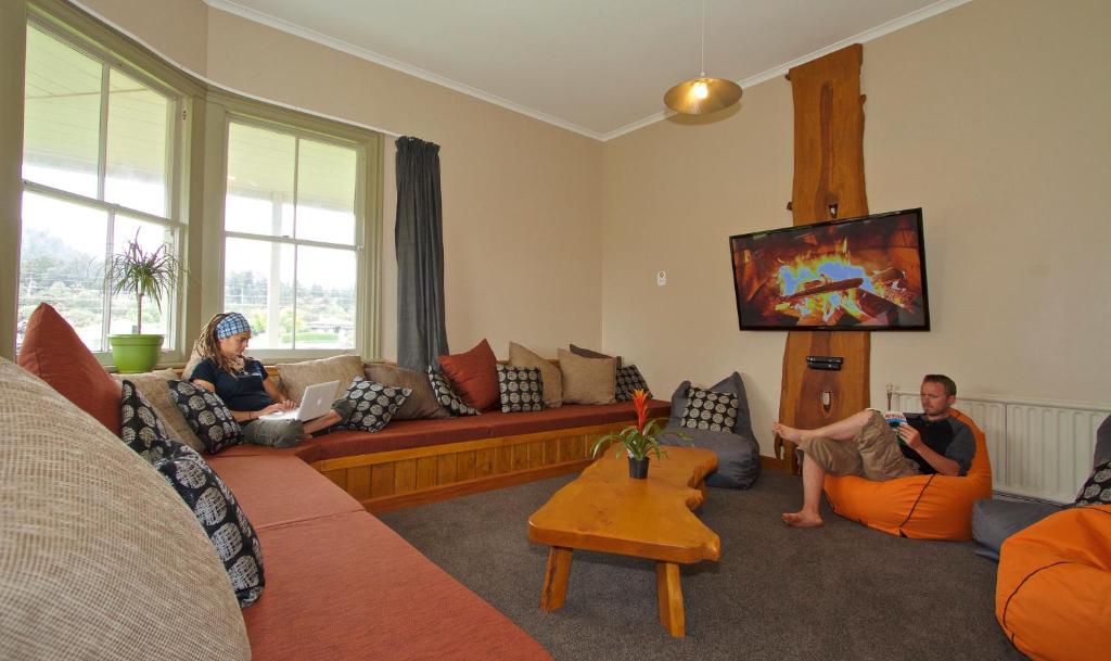 two people sitting in a living room watching tv at Station Lodge in Ohakune