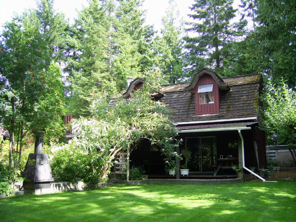 a house with a green yard with a tree at Garden House in Courtenay