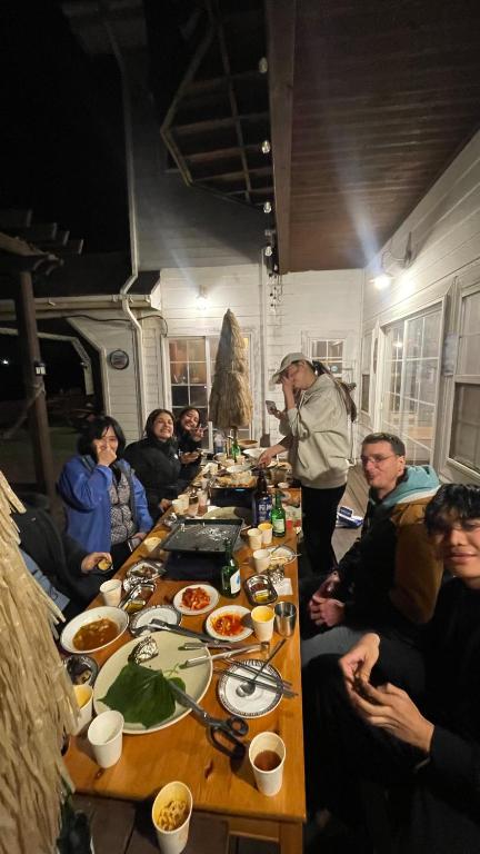 a group of people sitting around a long table with food at 버킷 제주 - Bucket Jeju in Seogwipo